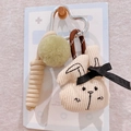 Detail of corduroy bunny keychain with plush ball, woven rope, and heart clasp - Bunny