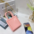 Close-up of pink PVC jelly handbag featuring gold pyramid studs in a lifestyle setting - Pink