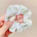 Detail shot of a white mesh scrunchie featuring elegant green floral patterns - Green Tiny Flowers