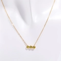 Detalle de collar dorado con tres circonitas verdes engastadas en bisel horizontal - Noviembre