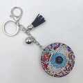 Silver Evil Eye keychain with colorful rhinestones and black tassel on white background - Multi-color