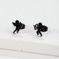 Detail shot of matte black cupid angel silhouette stud earrings on white stone display - Cupid / Black
