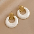Detail of vintage gold geometric earrings with white resin hoops on silk fabric - White