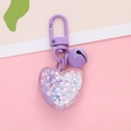 Detailed shot of purple heart keychain with bell and iridescent star sequins inside - Purple