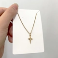 Dettaglio di una collana minimalista con pendente a stella dorata su carta da esposizione bianca - DN108 Luce Stellare