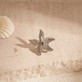 Macro shot of silver starfish ear clip with fine texture on a natural sandy beach surface - Clip Earring - Silver Spotted Starfish