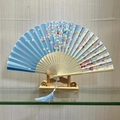 Blue folding fan with cherry blossom pattern and bamboo ribs featuring a blue tassel - Flower Clusters (Blue)