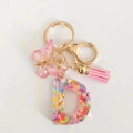 Detail of resin letter D keychain with pink sequins, butterfly charm and suede tassel - Letter D