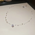Dettaglio di una collana a due strati con ciondolo in zircone e perle su filo trasparente - Argento