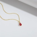 Detailaufnahme eines roten Glastropfen-Anhängers an einer feinen goldenen Halskette - Rot