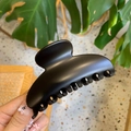 Close-up of matte black hair claw clip with rounded crescent design in hand - 10cm Yuanbao Claw / Matte Black