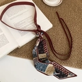 Macro shot of vintage burgundy leather belt with a patterned silk scarf and floral tassels - Red