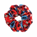 Detail view of red knit fabric scrunchie with colorful geometric patterns on white background - Red