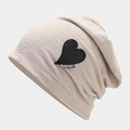 Detailed knit texture of a beige slouchy beanie featuring a black leather heart patch - M (56-58cm) / Beige