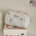 Detail van witte gewatteerde make-uptas met roze strikpatroon en ritssluiting - Roze Satijnen Strik - Achthoekige Tas