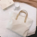 Detail of minimalist tote bag with leather handles and textured woven fabric material - White