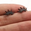 Macro view of tiny black stainless steel fan-shaped stud earring on a finger - Sun Radiant Style (680) / Black