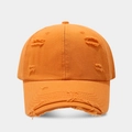 Close-up of orange distressed cotton baseball cap with ripped details and vintage edges - Orange