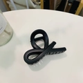 Detailed macro view of a matte black shark hair claw clip with a cross knot design - Matte Black