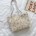 Beige strooien draagtas met groene bladborduring en een grote witte kanten strik - Broken Wit