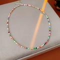 Gros plan d'un collier en perles de verre colorées avec fermoir mousqueton argenté - Coloré