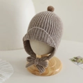 Detailed knit texture of khaki winter baby hat with top pompom and decorative bow tie - 2-5 Years Old / Gray