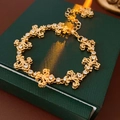 Nahaufnahme eines goldenen Vintage Fleur-de-lis Armbands mit Kristallen auf Geschenkbox - Gold