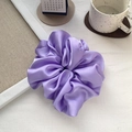 Macro detail of lavender satin scrunchie with soft silk texture and elegant pleats - Purple