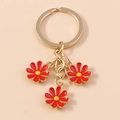 Golden metal keychain featuring three red daisy flower charms with yellow centers - Red