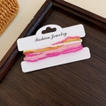 Close-up of pink and gold multi-layer beaded star bracelets on a white display card - Pink 6-Piece Set
