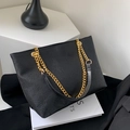 Dettaglio della pelle nera martellata e della tracolla a catena dorata della borsa tote - Nero