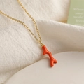 Detailed view of the orange coral antler pendant on a gold chain necklace for women - Orange
