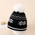 Detailed texture of black winter knit hat with white snowflakes and large faux fur pompom - Approx. 3-10 years old / Black