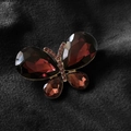 Spilla a farfalla dorata con cristallo rosso scuro e strass rosa su fondo nero - Viola