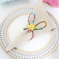 Close-up of a bunny ear napkin ring with pine needles and berries on a linen napkin - Rabbit Head Napkin Ring with Yellow Flower
