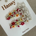 Close-up of handmade floral embroidery and pearl flower detail on beige BB hair clips - White