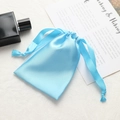 Light blue satin drawstring bag shown with perfume bottle on textured background - Sky Blue