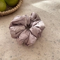 Détail d'un chouchou géant en soie rose sur tissu tricoté beige sous une lumière naturelle - Violet