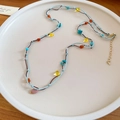 Dettaglio della collana bohémien in corda intrecciata con perline di pietre colorate - Colorato