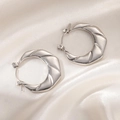 Detail of silver stainless steel textured earrings on a white silk fabric background - Origami Style Round Earrings (0231)