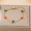 Close-up of gold butterfly bracelet with red and black charms on a metal display stand - Black + Red (KB187205-BI)