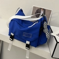 Blaue Nylon-Umhängetasche mit weißem Gurt und Schachbrett-Anhänger in schlichter Umgebung - Mit Anhänger / Blau