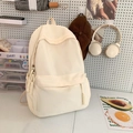 Zaino minimalista in nylon crema per studenti esposto su una scrivania decorata - Bianco