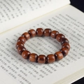 Détail de perles en bois Dalbergia avec rayures de tigre naturelles sur un livre ouvert - Perles Classiques en Palissandre / 12mm*17 Perles