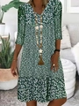Detailed close-up of a green floral V-neck dress with a long wooden bead necklace and tassel - S / Tops / Green