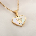 Gold heart necklace with white mother of pearl inlay and metal letter W on silk background - Letter W