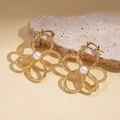 Detalle de pendientes de flor dorada con pétalos texturizados y una perla blanca central - Dorado