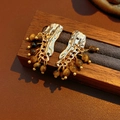 Close-up of vintage gold earrings with textured waves and dangling tiger eye stone beads - Gold Brown
