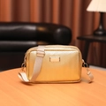 Chic golden crossbody camera bag with wave texture and adjustable strap on a wooden table - Folded Gold