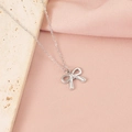 Gros plan d'un collier pendentif nœud argenté sur pierre beige et soie rose - Style Nœud Papillon 7 (7#)